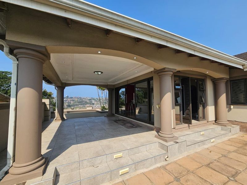 A spacious covered patio featuring tiled flooring, decorative columns, and recessed lighting, offering seamless indoor-outdoor flow through large sliding glass doors.