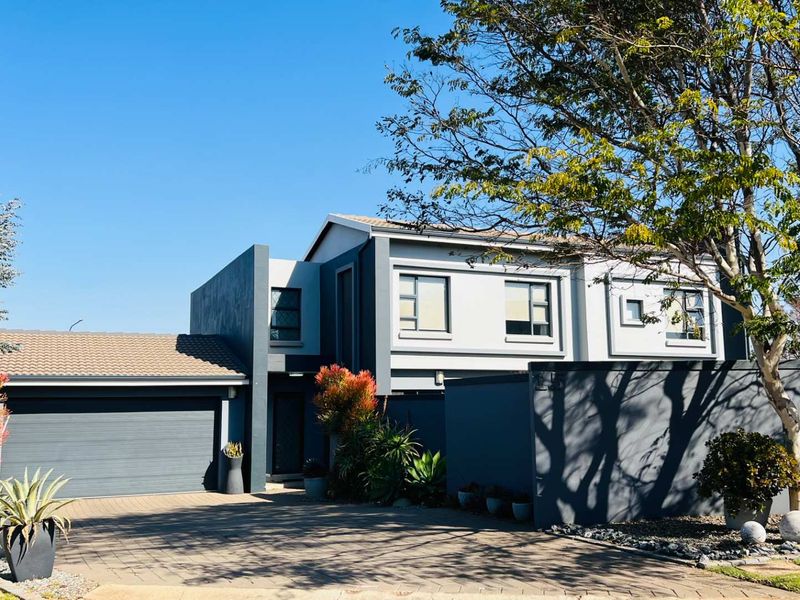 Modern double-storey residential property featuring a paved driveway, double garage, and contemporary grey exterior facade with well-maintained landscaping.