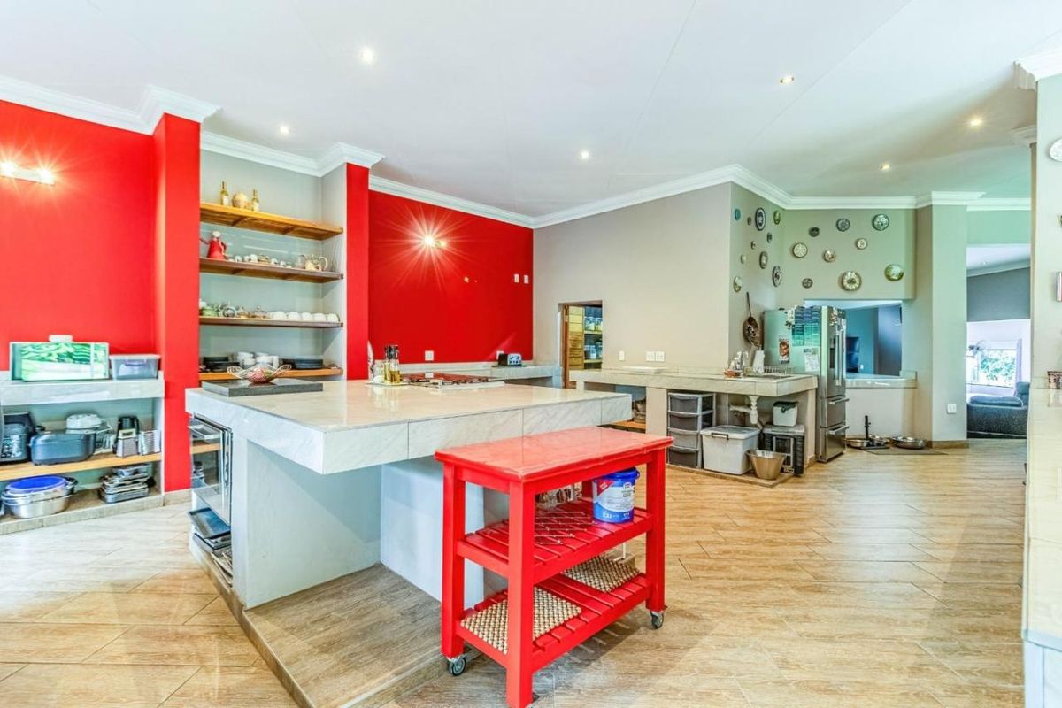 Spacious kitchen featuring a large central island with stone countertop, built-in shelving, and tiled flooring throughout.