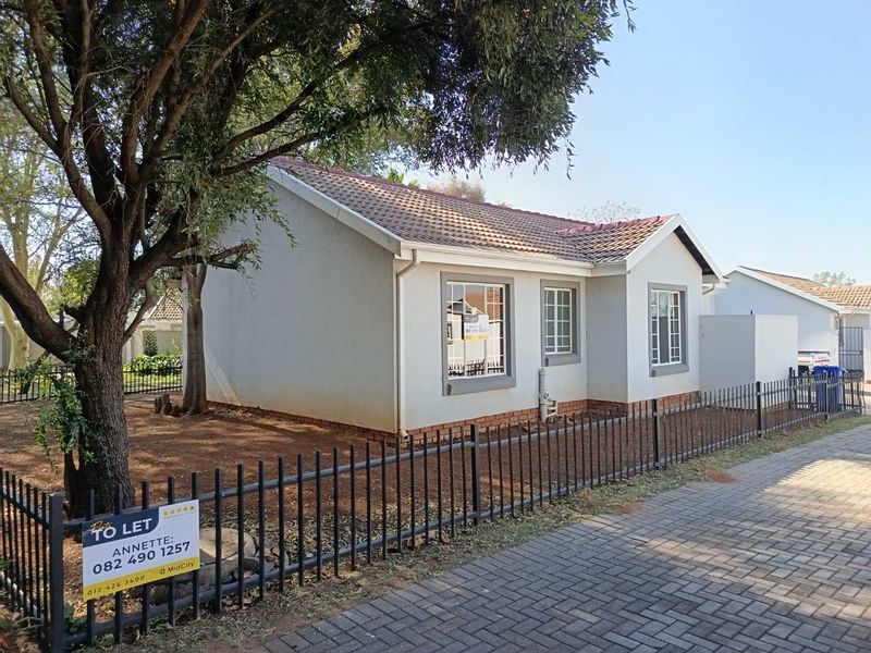 A well-maintained single-story residential unit featuring a tiled roof, plastered exterior, and secure metal perimeter fencing with a paved driveway.