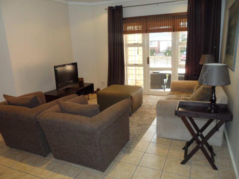 A comfortable living room featuring tiled flooring and a glass sliding door providing access to the exterior.