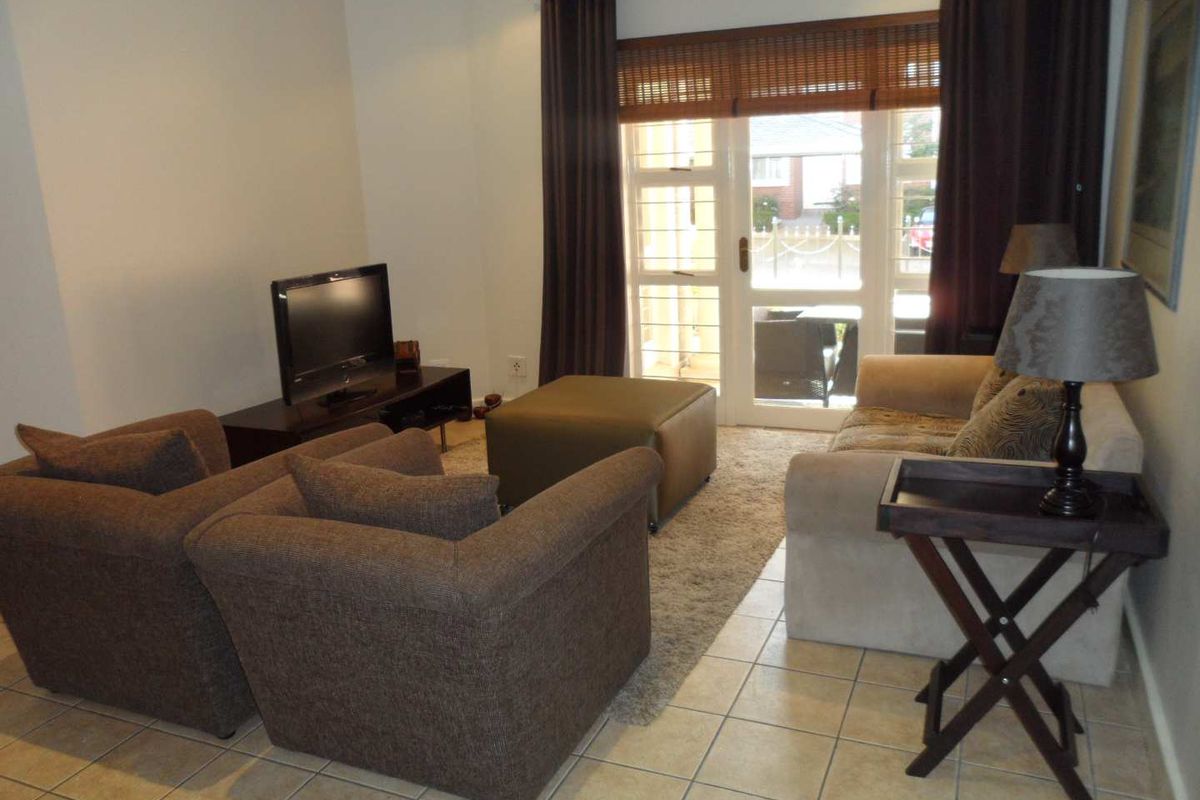 A comfortable living room featuring tiled flooring and a glass sliding door providing access to the exterior.