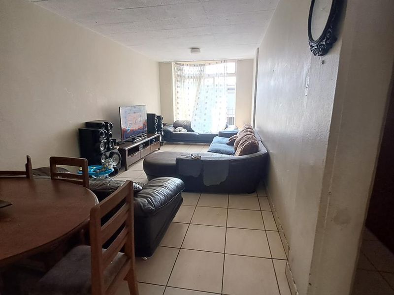 Open plan living and dining area featuring tiled flooring and access to a balcony through a sliding glass door.