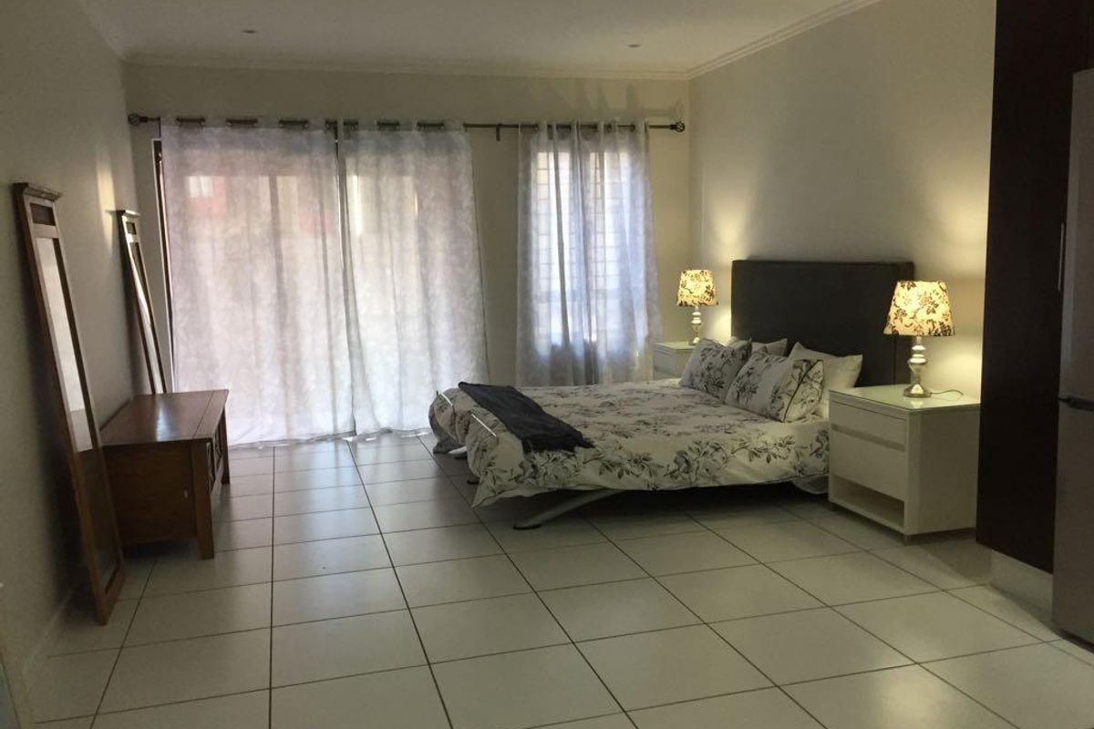 Spacious bedroom featuring large tiled flooring, recessed ceiling lighting, and sliding glass doors providing access to an outdoor area.