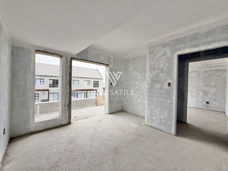 An unfinished interior living space featuring raw plastered walls and concrete flooring, offering a blank canvas for custom renovation and interior design.