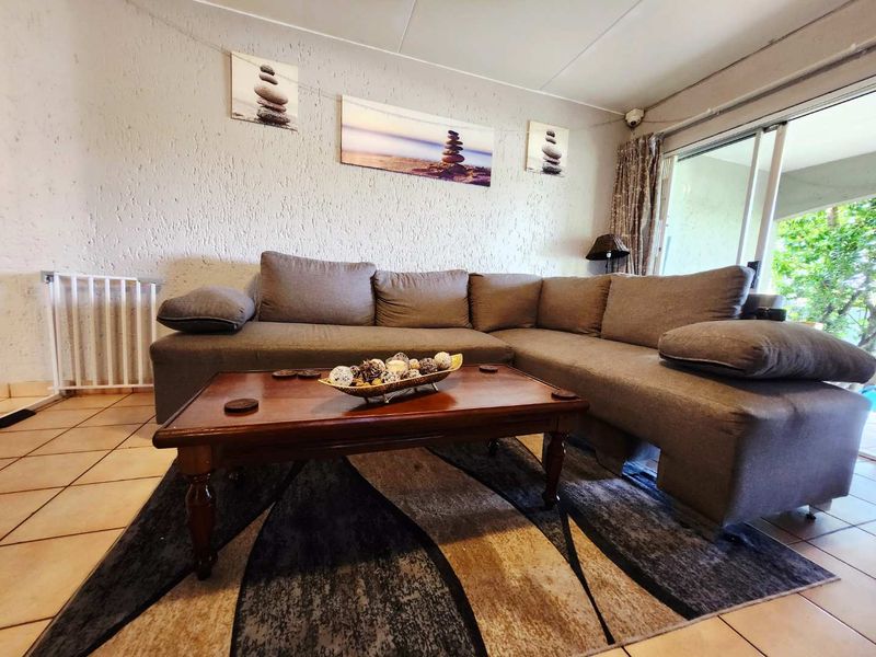 A living room featuring tiled flooring and a sliding glass door providing access to the outdoor area.