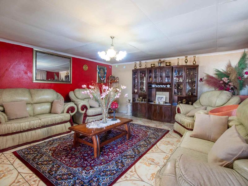 A living room featuring tiled flooring and a central ceiling light fixture, with visible wear on the ceiling panels.