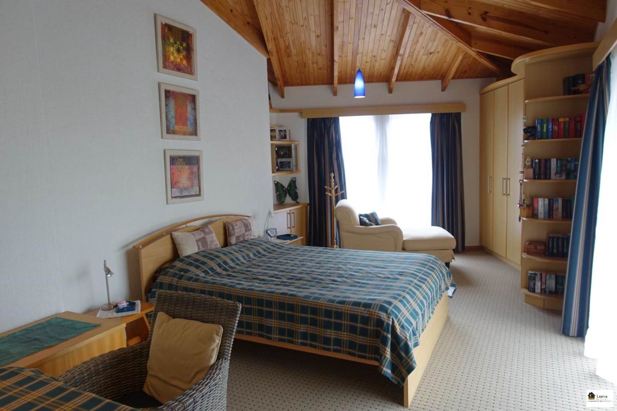 Spacious bedroom featuring a vaulted timber-clad ceiling, built-in cabinetry, and large windows allowing for ample natural light.