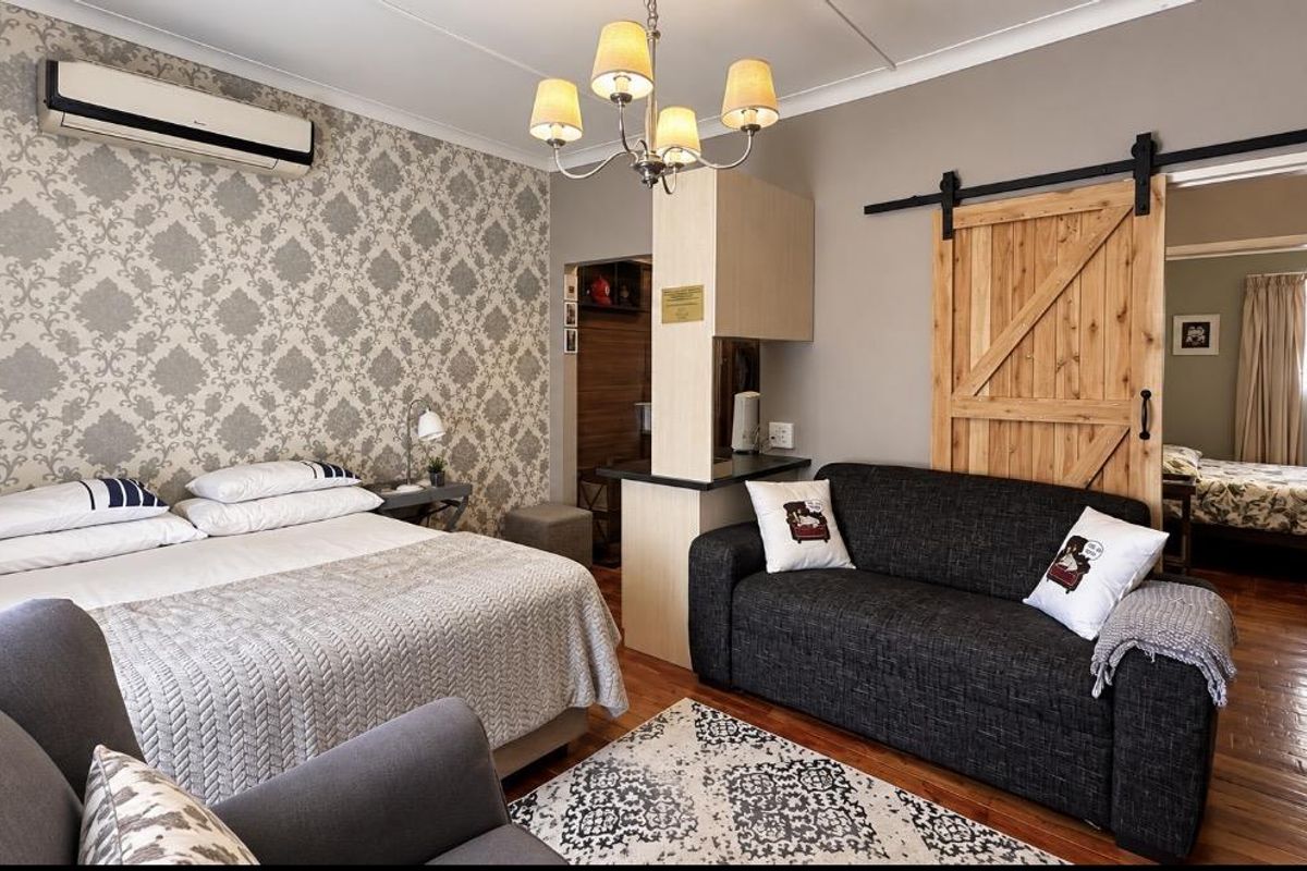 A well-maintained bedroom featuring hardwood flooring, a decorative feature wall, a split-system air conditioner, and a rustic sliding barn door leading to an adjacent room.