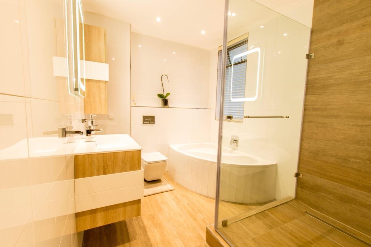 Modern bathroom featuring a wall-mounted vanity, integrated basin, wall-hung toilet, built-in bathtub, and a spacious glass-enclosed shower with contemporary finishes.
