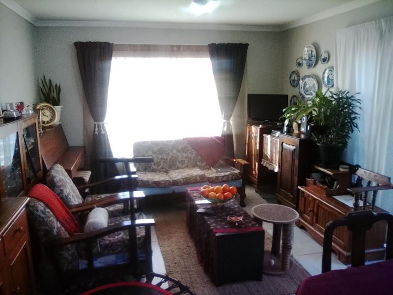 A living room featuring tiled flooring and a large window, providing natural light to the space.