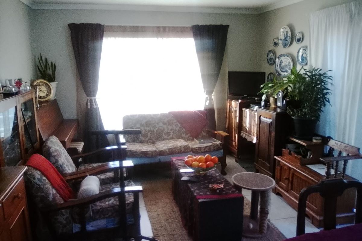 A living room featuring tiled flooring and a large window, providing natural light to the space.