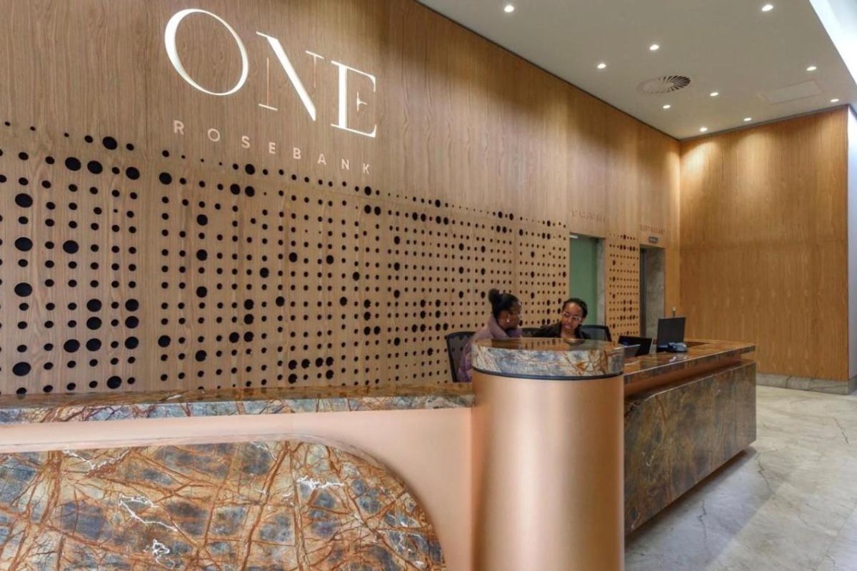 Modern reception area featuring a stone-topped desk, decorative wood paneling with integrated branding, and professional recessed lighting.