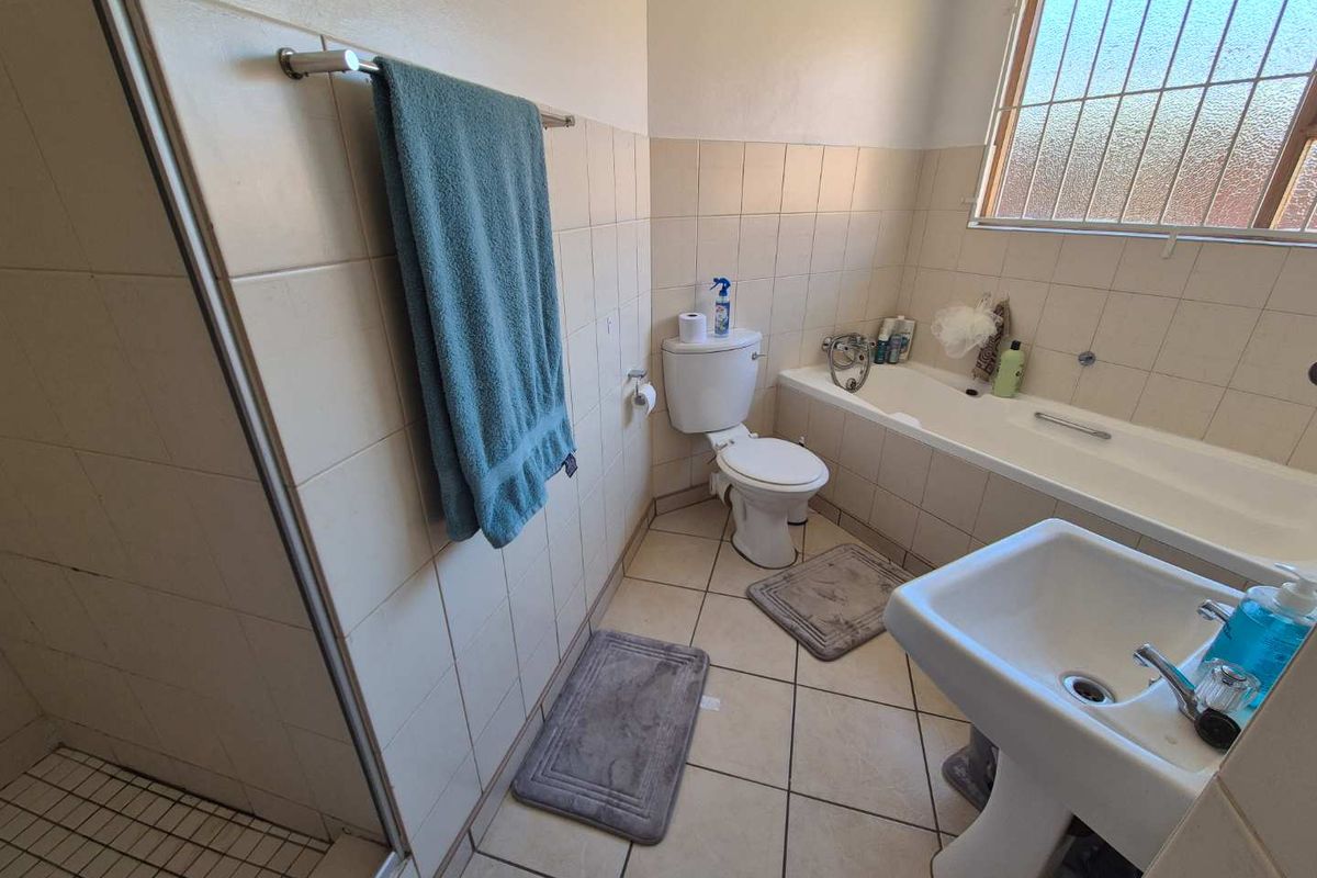 A functional bathroom featuring a pedestal sink, a built-in bathtub, a separate shower enclosure, and a toilet with tiled walls and flooring.