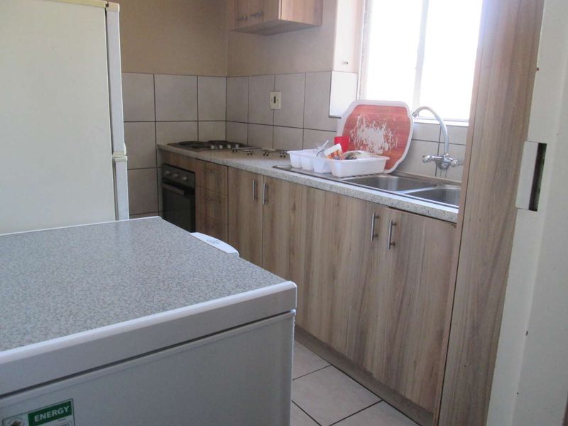 A functional kitchen featuring wood-look cabinetry, laminate countertops, a double basin sink, and built-in oven with hob.