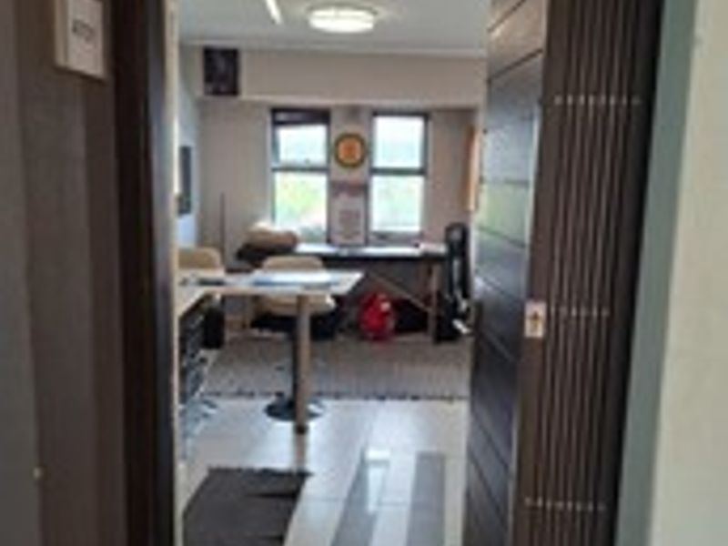 A functional office space featuring tiled flooring, large windows for natural light, and a sliding folding door entrance.