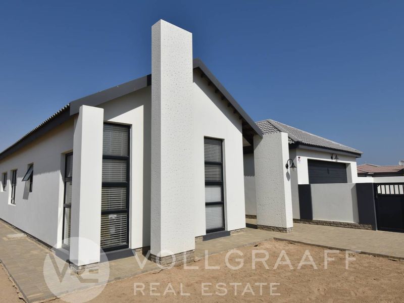 Modern single-story house exterior featuring a clean white facade, tiled roof, paved driveway, and integrated garage with secure gated access.