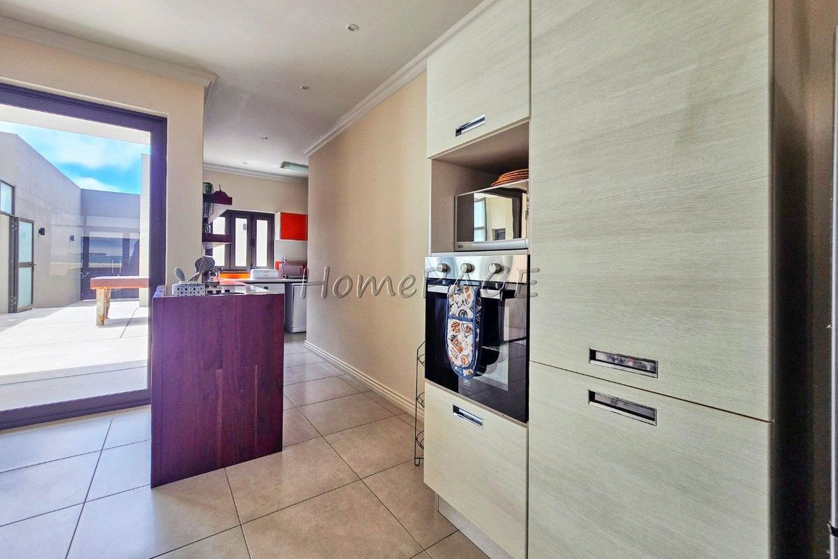 Modern kitchen featuring built-in oven, microwave housing, and tiled flooring, with seamless access to an outdoor patio area.