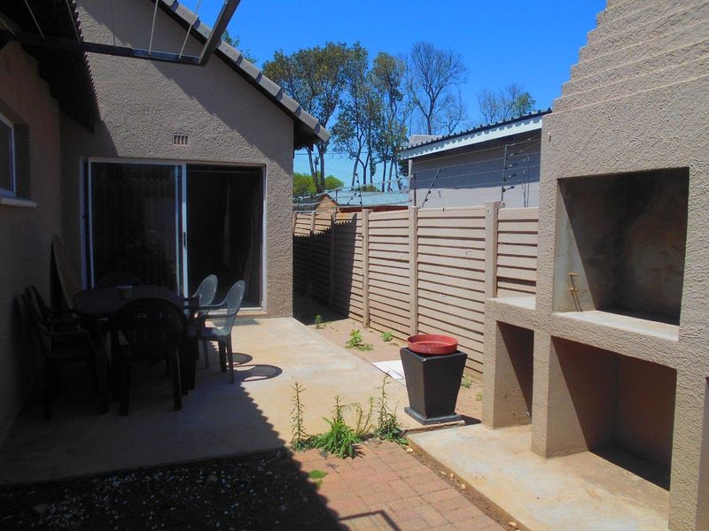 Outdoor patio area featuring a built-in braai, concrete flooring, and direct access to the interior via sliding glass doors.