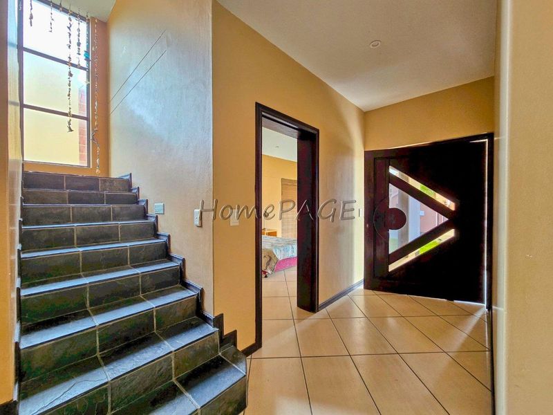 Entrance foyer featuring tiled flooring, a modern front door, and a staircase leading to the upper level with a tall window.