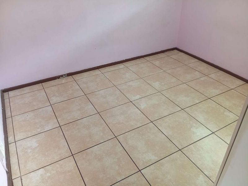 An empty bedroom featuring neutral ceramic floor tiles and painted walls, providing a blank canvas for potential interior design updates.