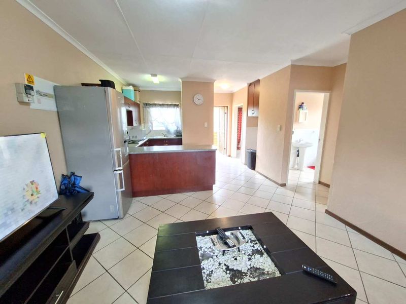 Open plan living area featuring tiled floors and a functional kitchen with built-in cabinetry and countertop space.