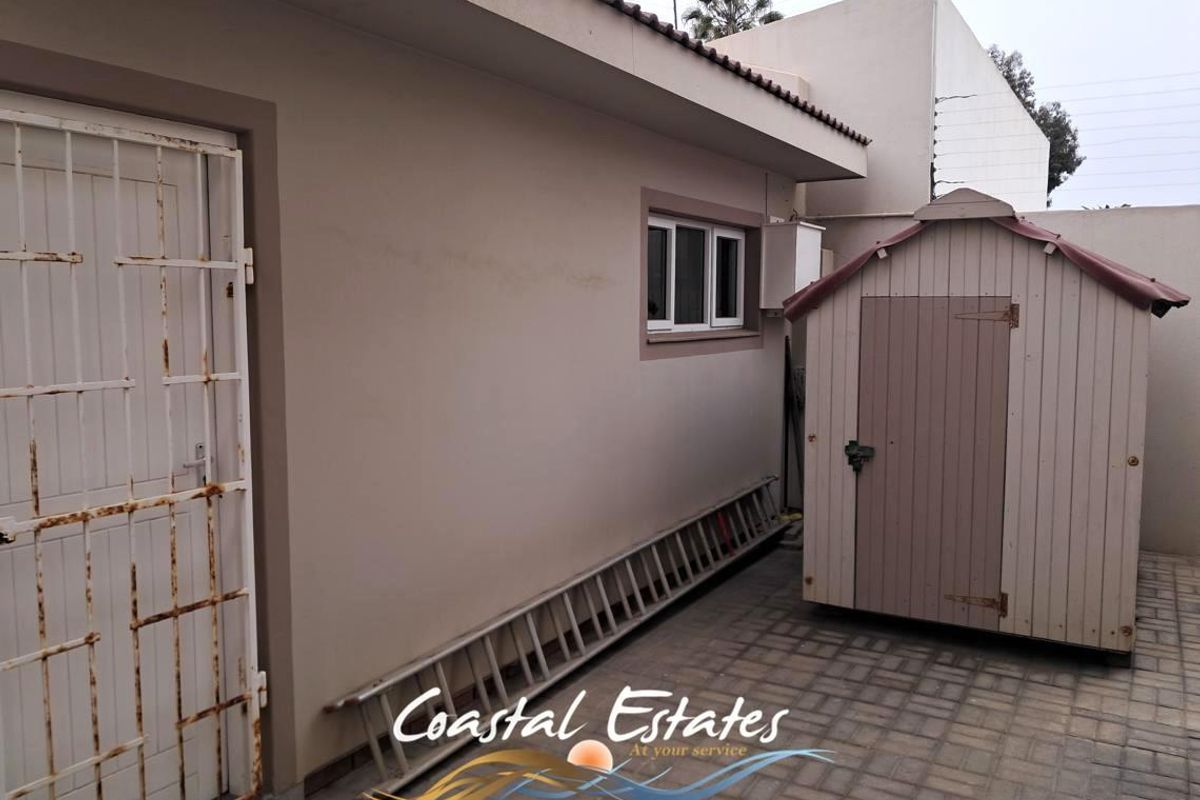 A paved rear courtyard area featuring a security gate and exterior wall access.