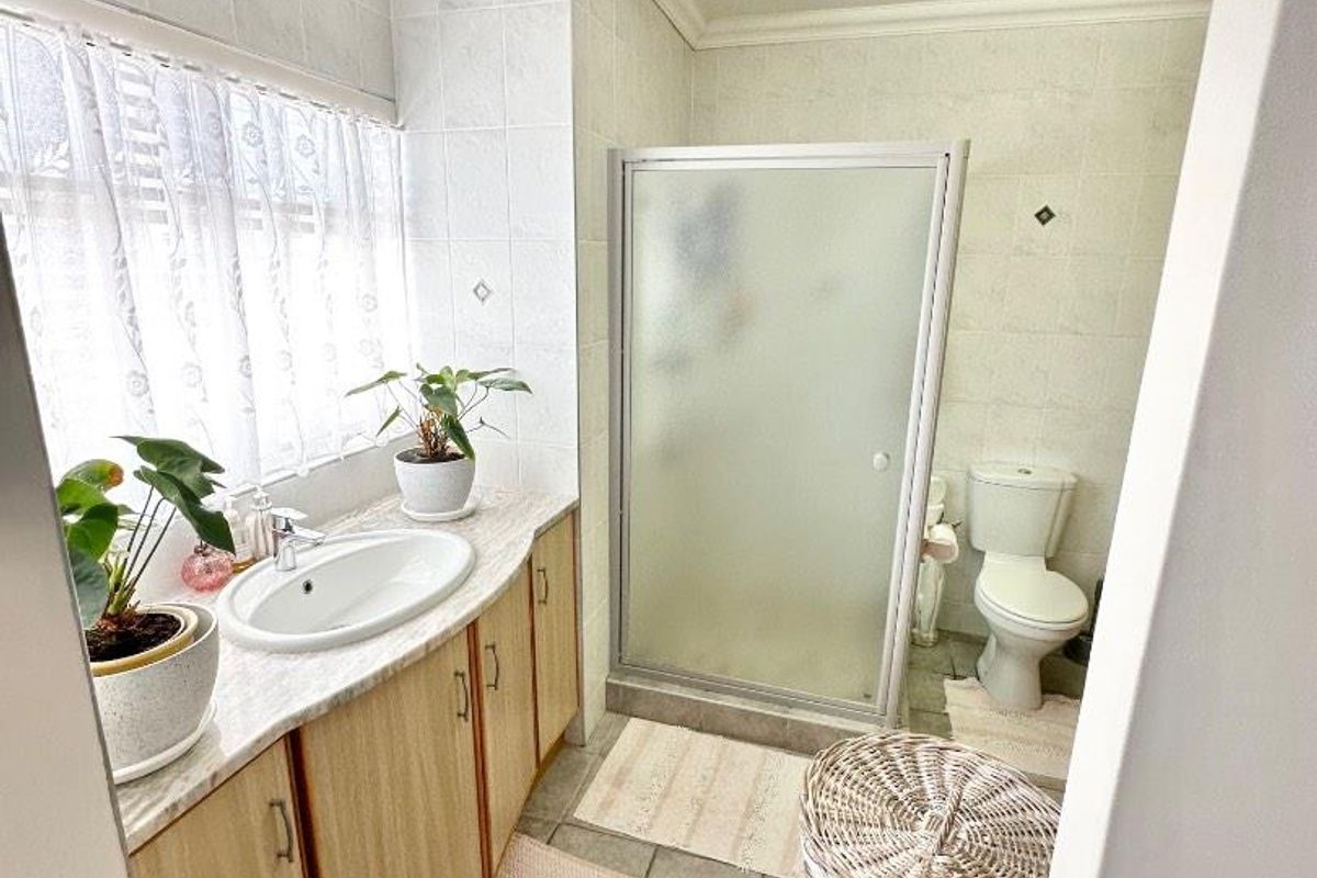 A functional bathroom featuring a vanity with laminate countertop, a walk-in shower with frosted glass enclosure, and a standard toilet.