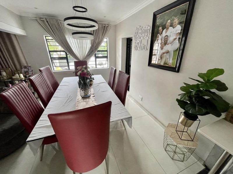 A well-maintained dining room featuring tiled flooring, modern pendant lighting, and large windows that provide ample natural light.