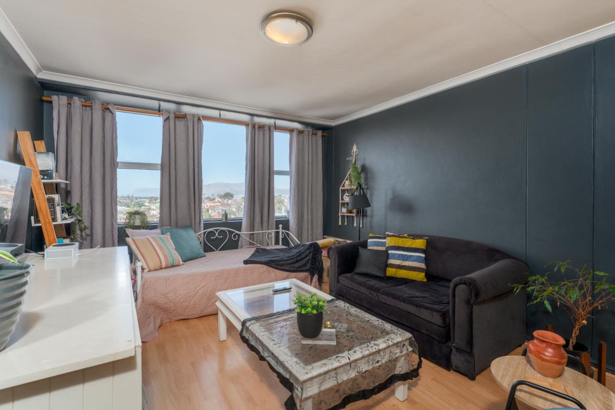 A living room featuring laminate flooring, coving, and large windows that provide natural light and expansive views.