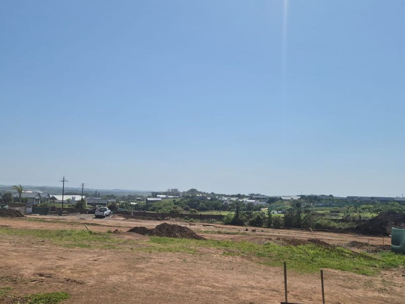 A wide-angle view of a vacant residential plot featuring cleared land and surrounding neighborhood views, ready for new construction.