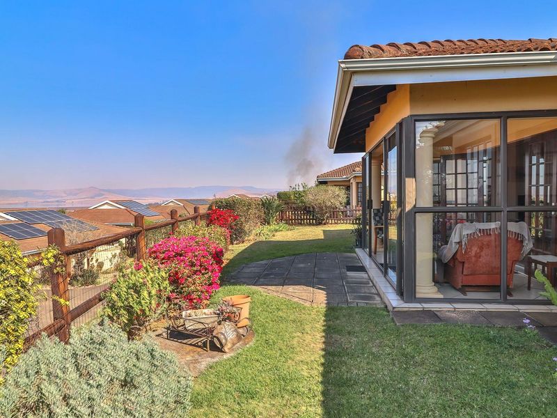 Rear exterior view of the townhouse featuring an enclosed patio, paved garden path, and scenic landscape views.