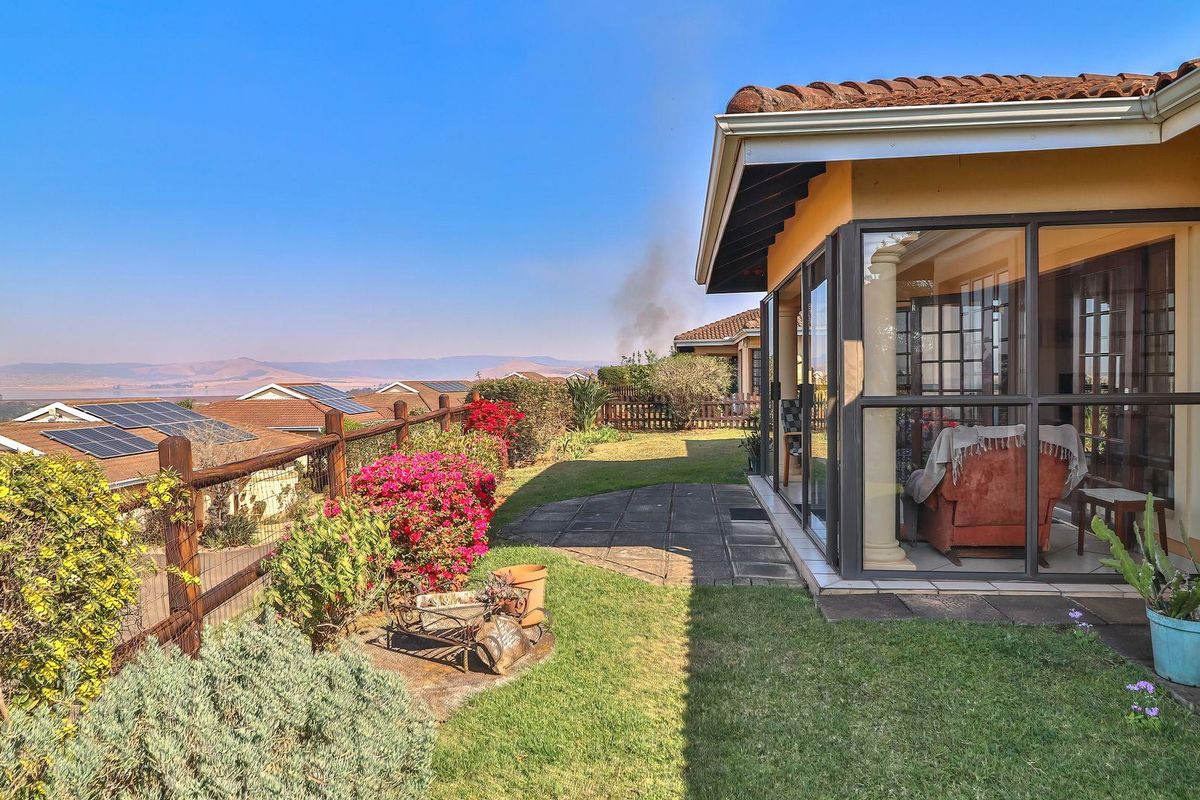 Rear exterior view of the townhouse featuring an enclosed patio, paved garden path, and scenic landscape views.