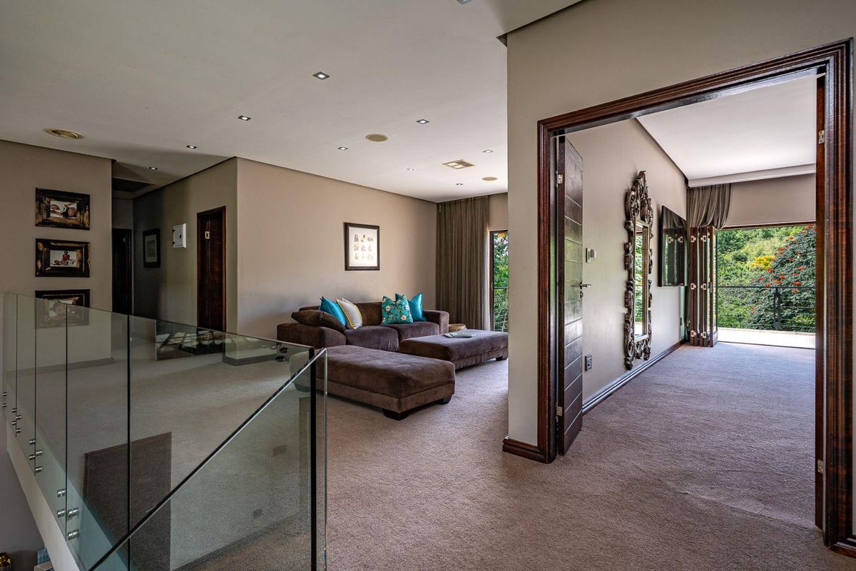 Spacious upper-level living area featuring a glass balustrade, recessed ceiling lighting, and direct access to a private balcony with scenic views.