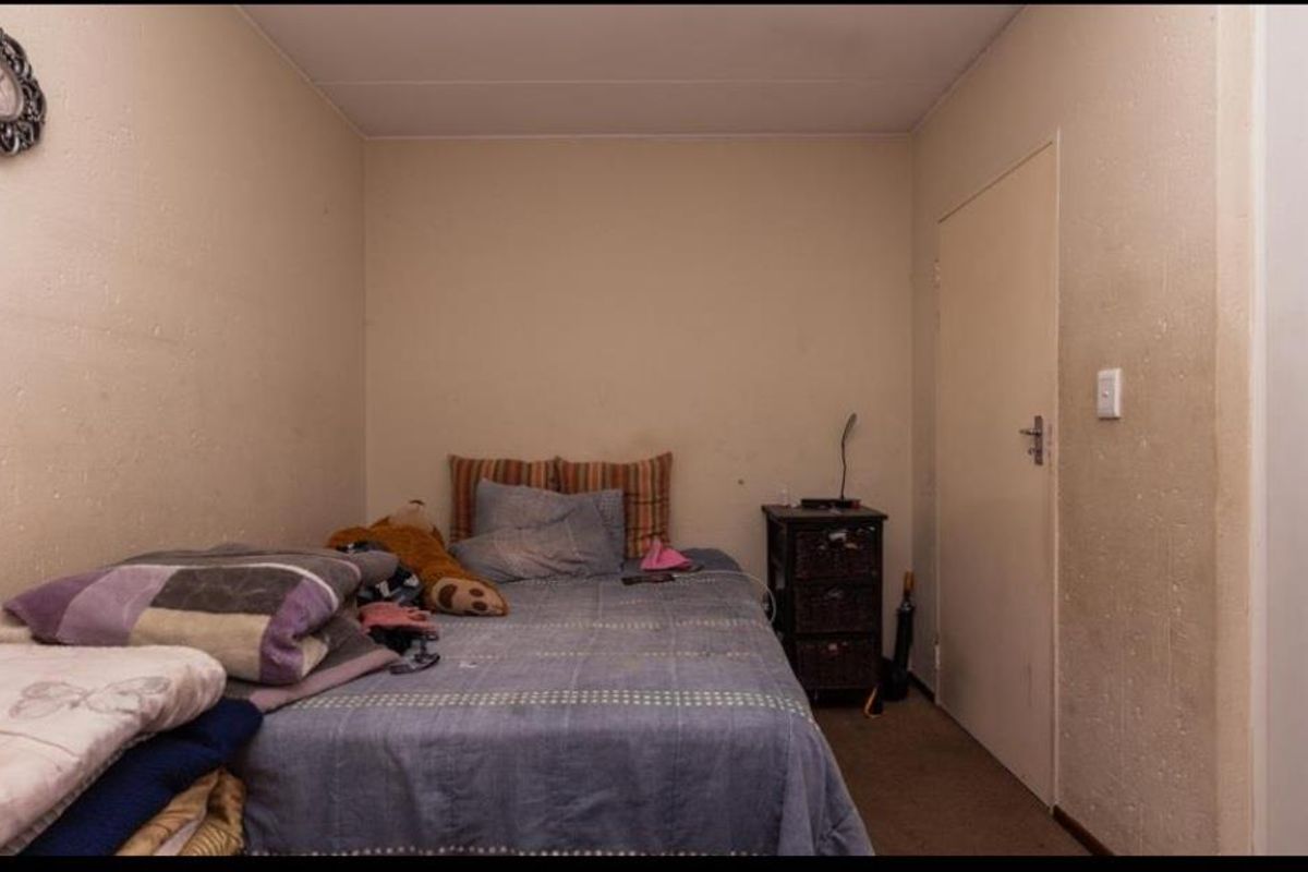 A compact bedroom featuring neutral wall finishes and a standard interior door, providing a functional space for rest.