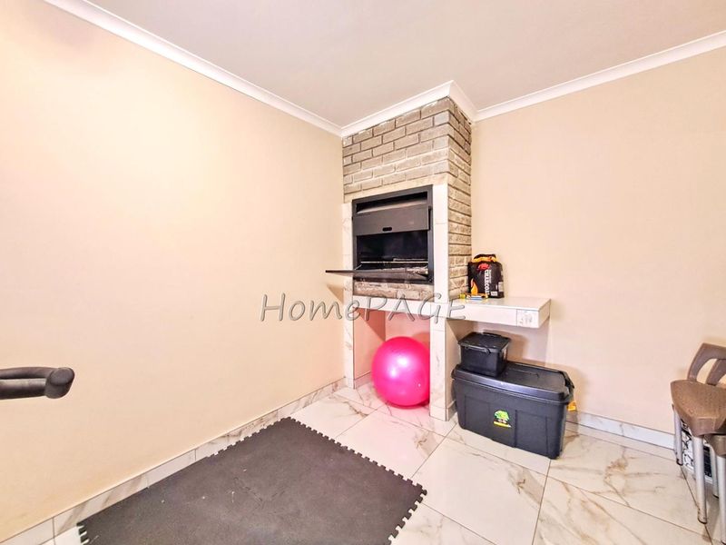 A covered patio area featuring a built-in brick braai, tiled flooring, and neutral wall finishes, suitable for outdoor entertaining.