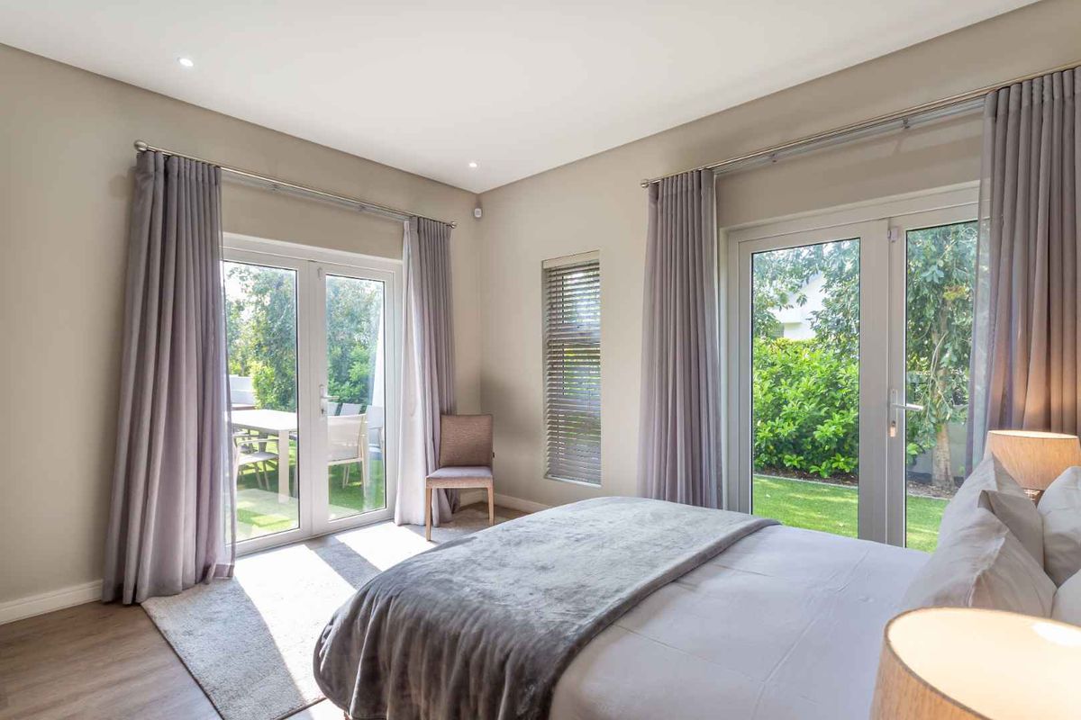Bright bedroom featuring laminate flooring, recessed lighting, and dual glass doors providing direct access to the garden.