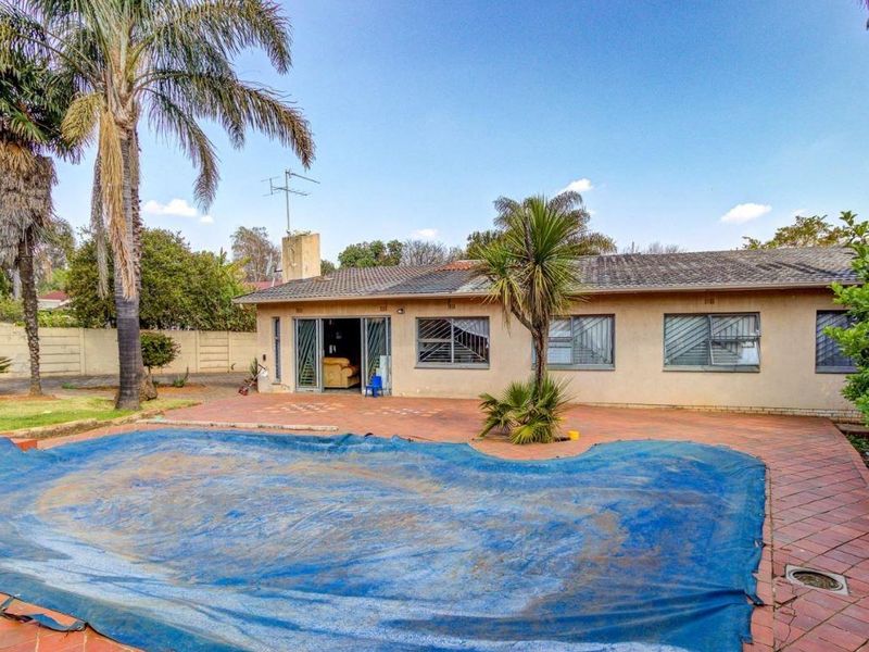 Rear exterior view featuring a swimming pool with cover, paved patio area, and access to the home via sliding doors.