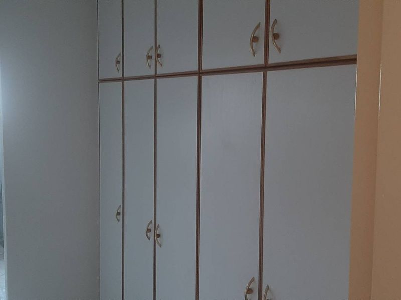 A bedroom featuring extensive built-in cupboards and direct access to an en-suite bathroom with tiled flooring.