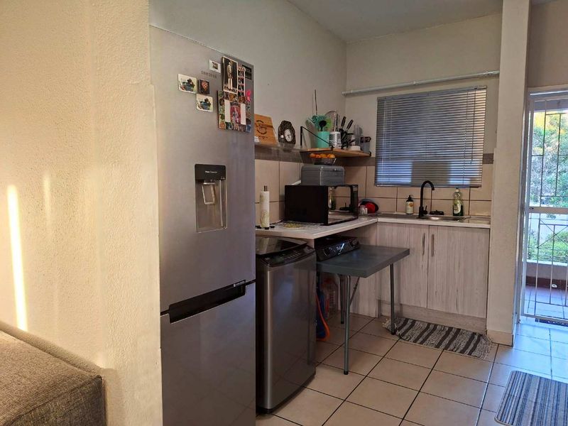 Compact kitchen area featuring tiled flooring, built-in cabinetry, a tiled backsplash, and a stainless steel sink with a modern faucet.