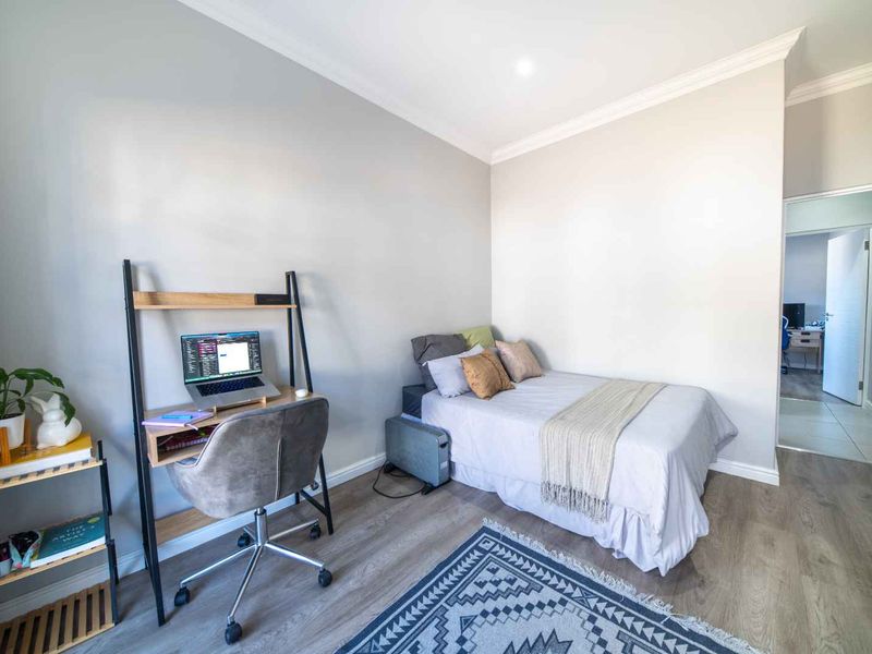 A well-maintained bedroom featuring modern laminate flooring, neutral wall tones, and recessed downlighting, providing a clean and functional living space.