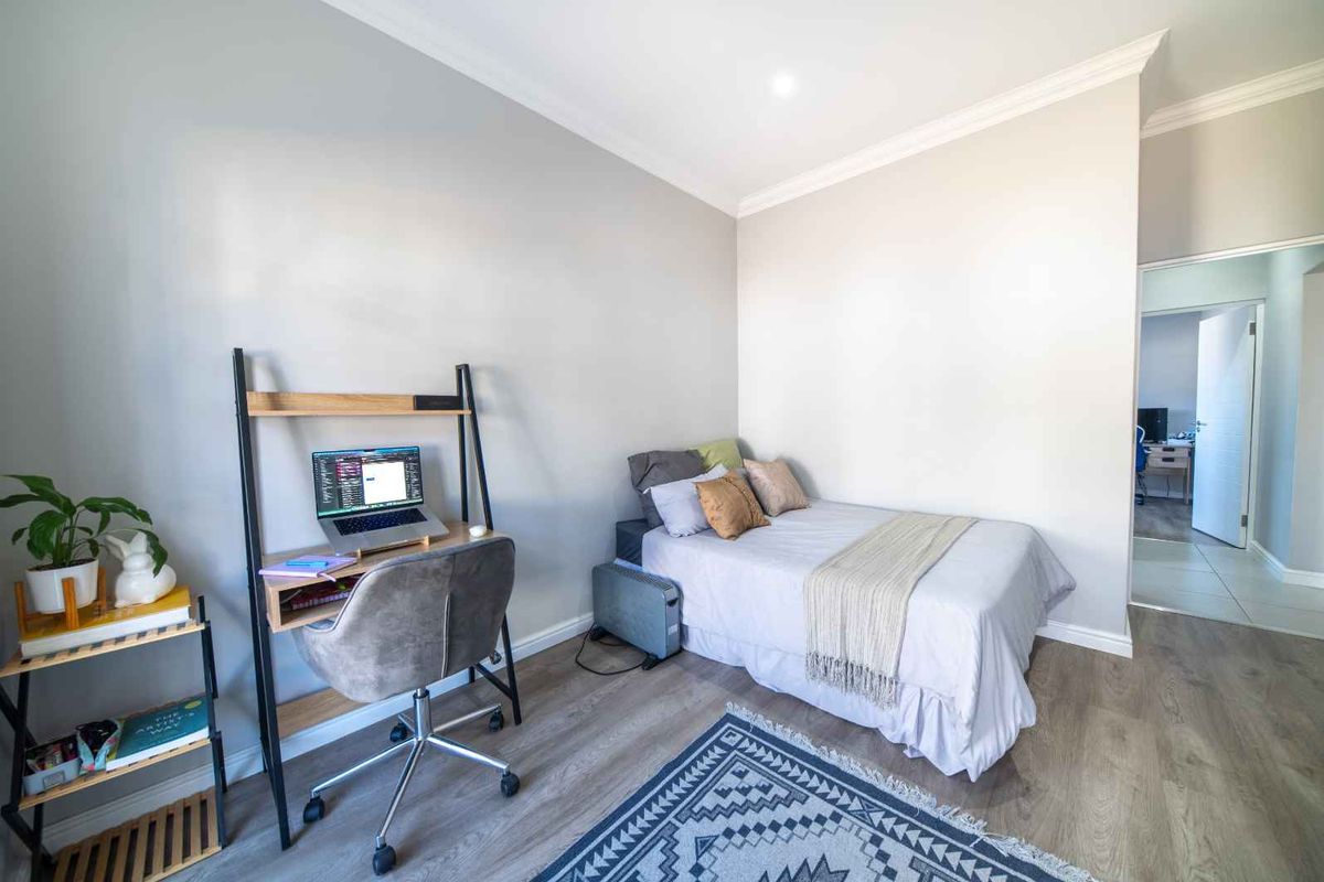 A well-maintained bedroom featuring modern laminate flooring, neutral wall tones, and recessed downlighting, providing a clean and functional living space.