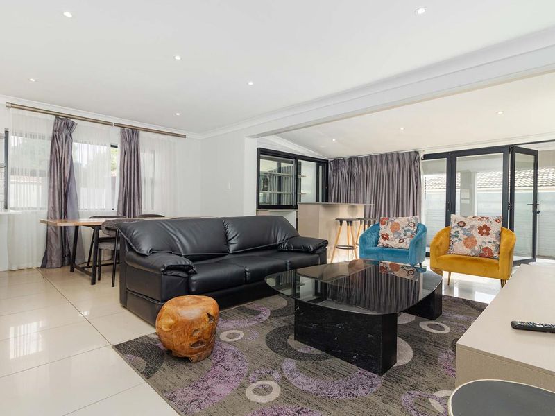 Spacious open-plan living and dining area featuring tiled floors, recessed lighting, and seamless access to the outdoor patio through modern bi-fold doors.