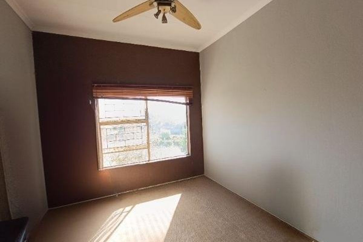 An empty bedroom featuring neutral walls, a ceiling fan, and carpet flooring, providing a blank canvas for personalization.