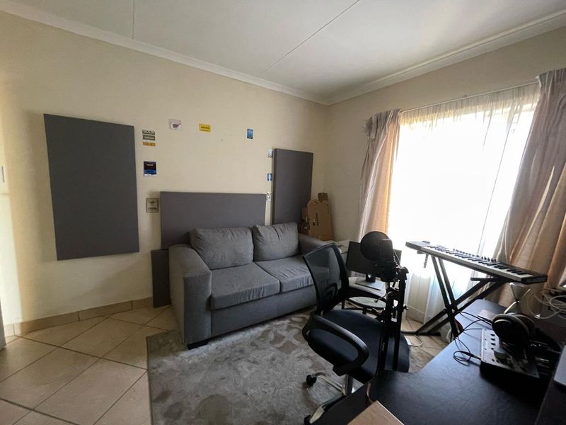 A bedroom space featuring tiled flooring and coved ceilings, currently utilized as a home office and studio area.