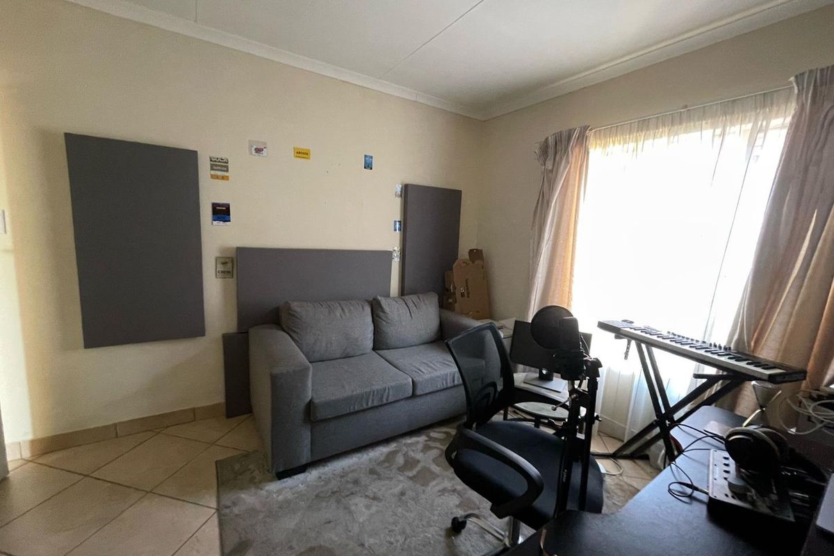 A bedroom space featuring tiled flooring and coved ceilings, currently utilized as a home office and studio area.