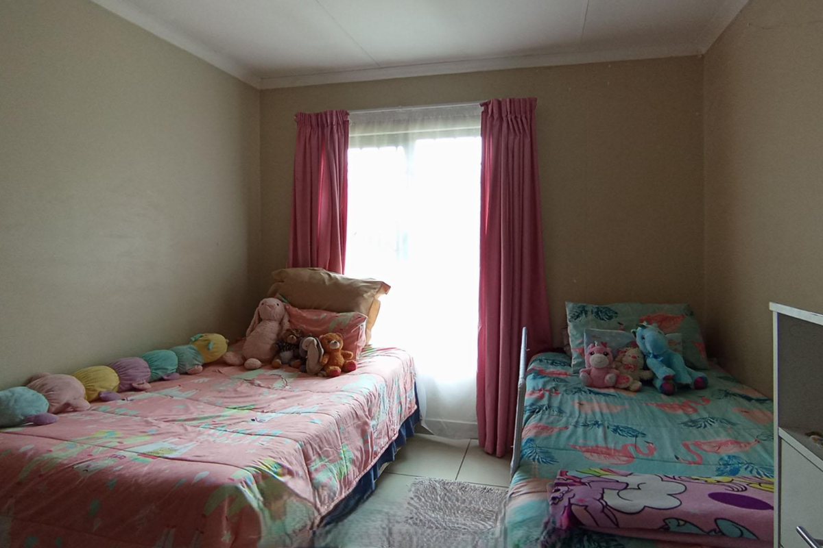 A functional bedroom featuring tiled flooring and a window with curtains, providing natural light.