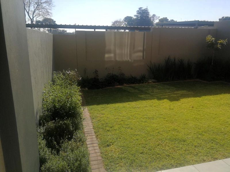 A private rear garden featuring a well-maintained lawn, brick edging, and high boundary walls providing privacy.
