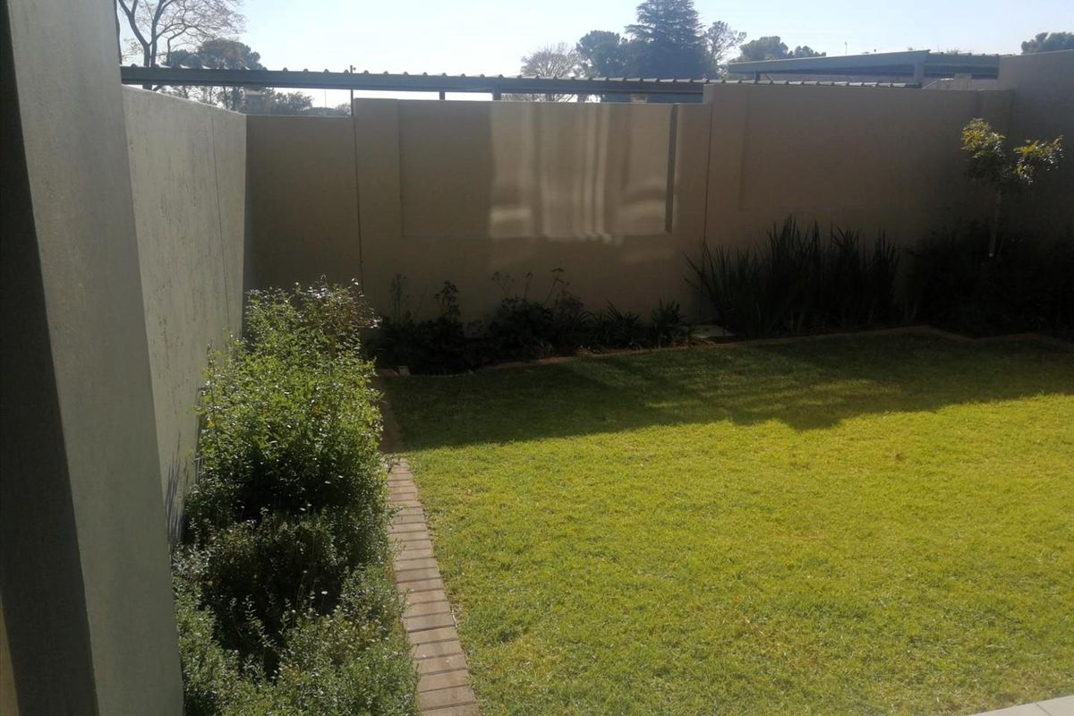 A private rear garden featuring a well-maintained lawn, brick edging, and high boundary walls providing privacy.