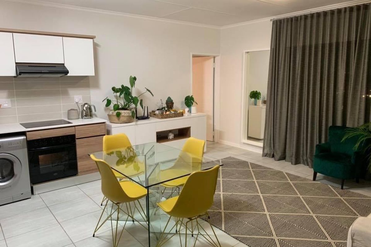 An open-plan living and kitchen area featuring modern cabinetry, built-in appliances, tiled flooring, and neutral wall finishes.